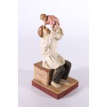 Russian Gardner style bisque porcelain figure of seated man holding baby aloft, red back stamp "by