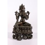 A 19th century Indian bronze Tara seated on a double lotus throne, with inset glass 'jewels', carved