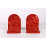 A pair of 20th century cinnabar book ends, of arched form, carved with a pair of children in a