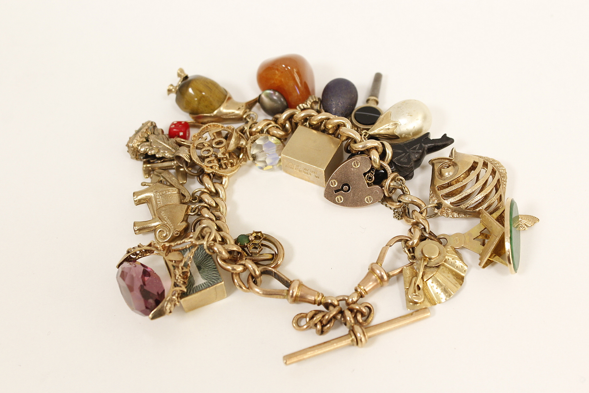 Gold hollow curb bracelet with various gem set and other charms, mostly 9ct gold.