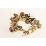 Gold hollow curb bracelet with various gem set and other charms, mostly 9ct gold.