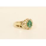 Diamond and emerald ring with an oval cluster flanked by brilliant set chevrons '14k'. Size 'N'.