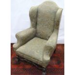 19th century upholstered wing back arm chair in the Jacobean style, with carved scrolling front