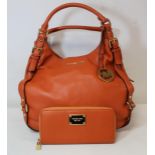 Michael Kors lady's handbag in orange leather with gilt hardware and matching zip around wallet.