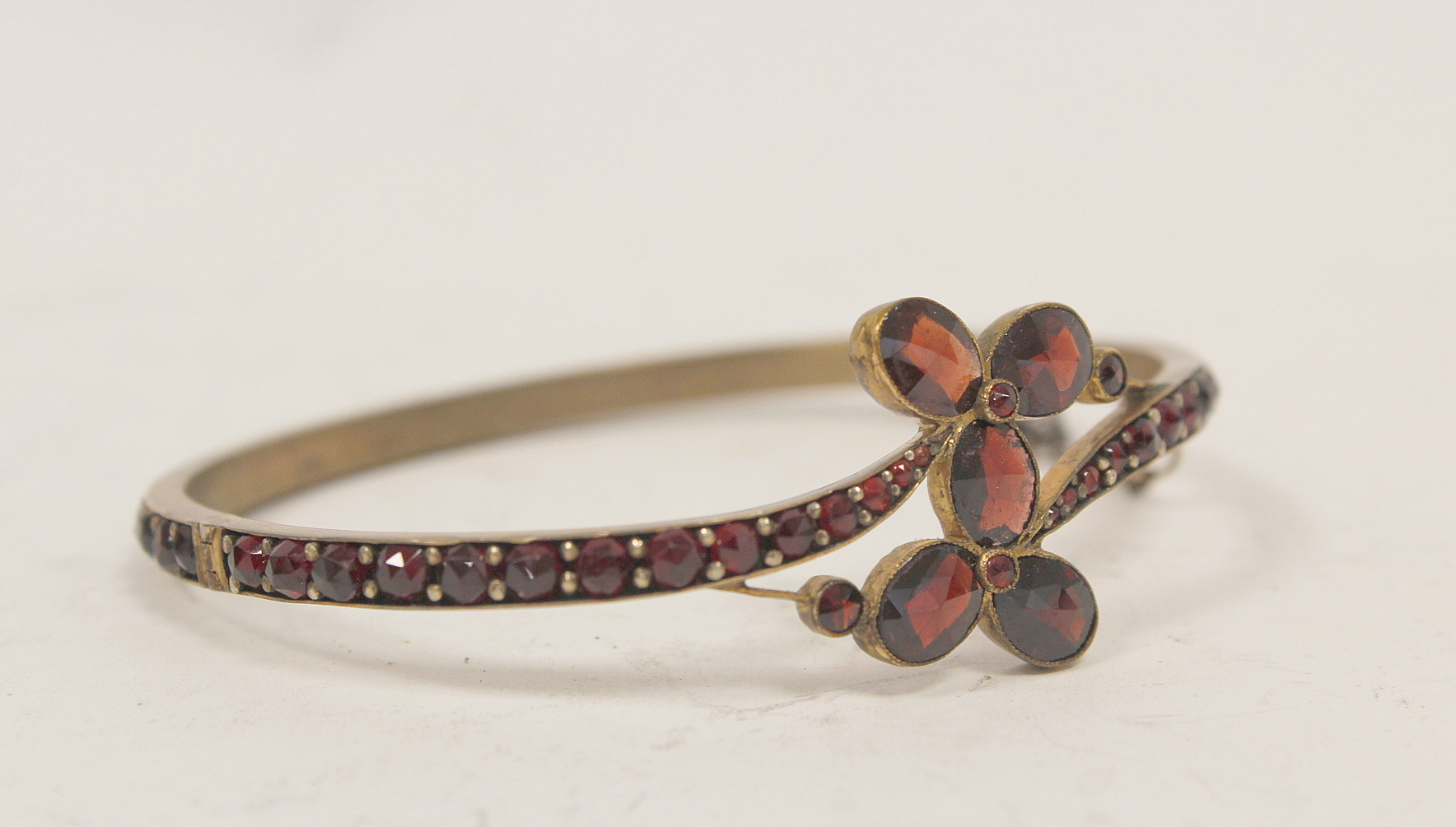 Victorian pyrope garnet hinged bangle in 'garnet' gold and a similar cluster brooch. (2). - Image 2 of 4