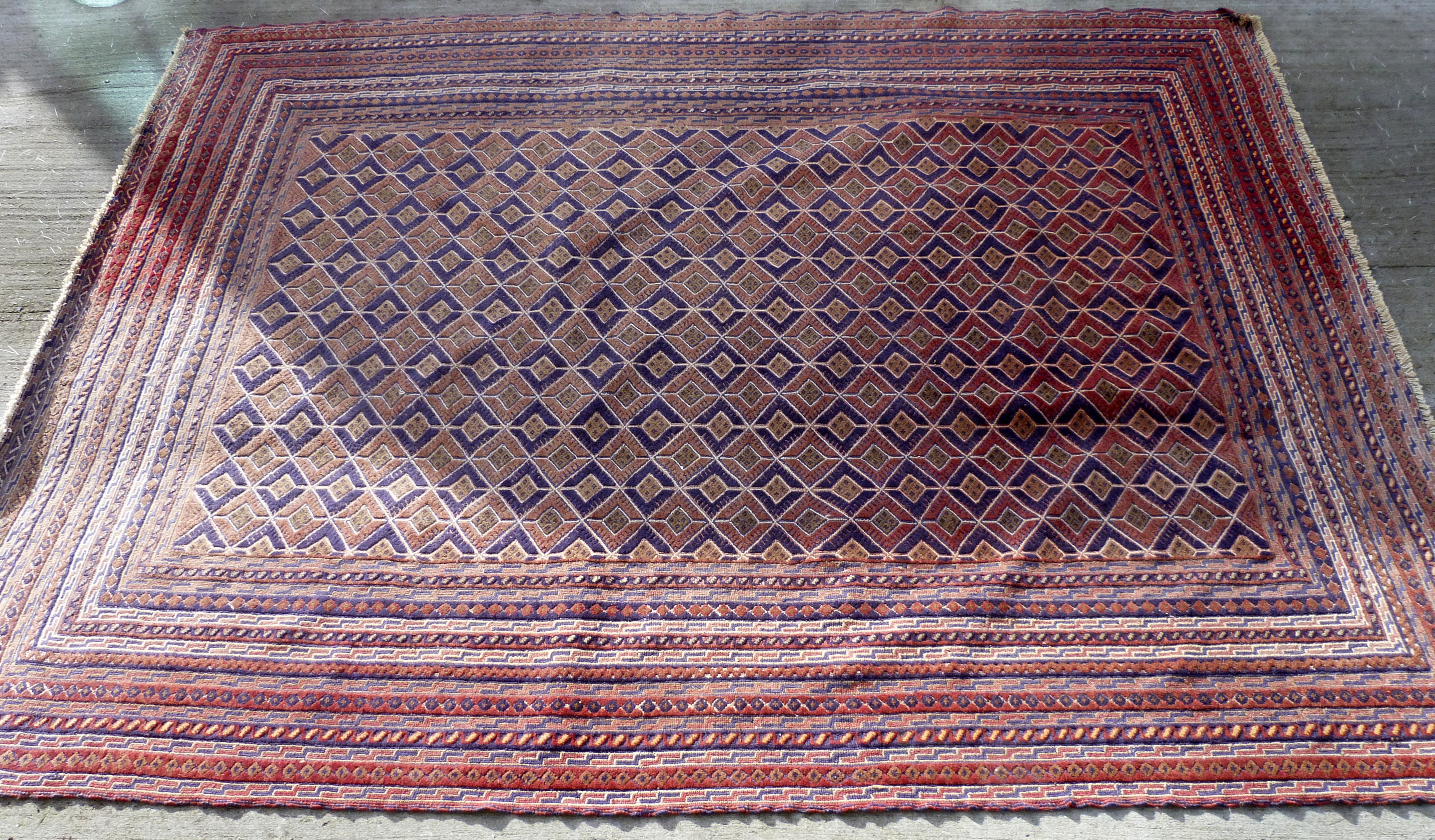 Afghan Mushwani wool carpet with diamond lattice field, in red, blue and ochre, 271cm x 203cm.