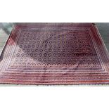 Afghan Mushwani wool carpet with diamond lattice field, in red, blue and ochre, 271cm x 203cm.