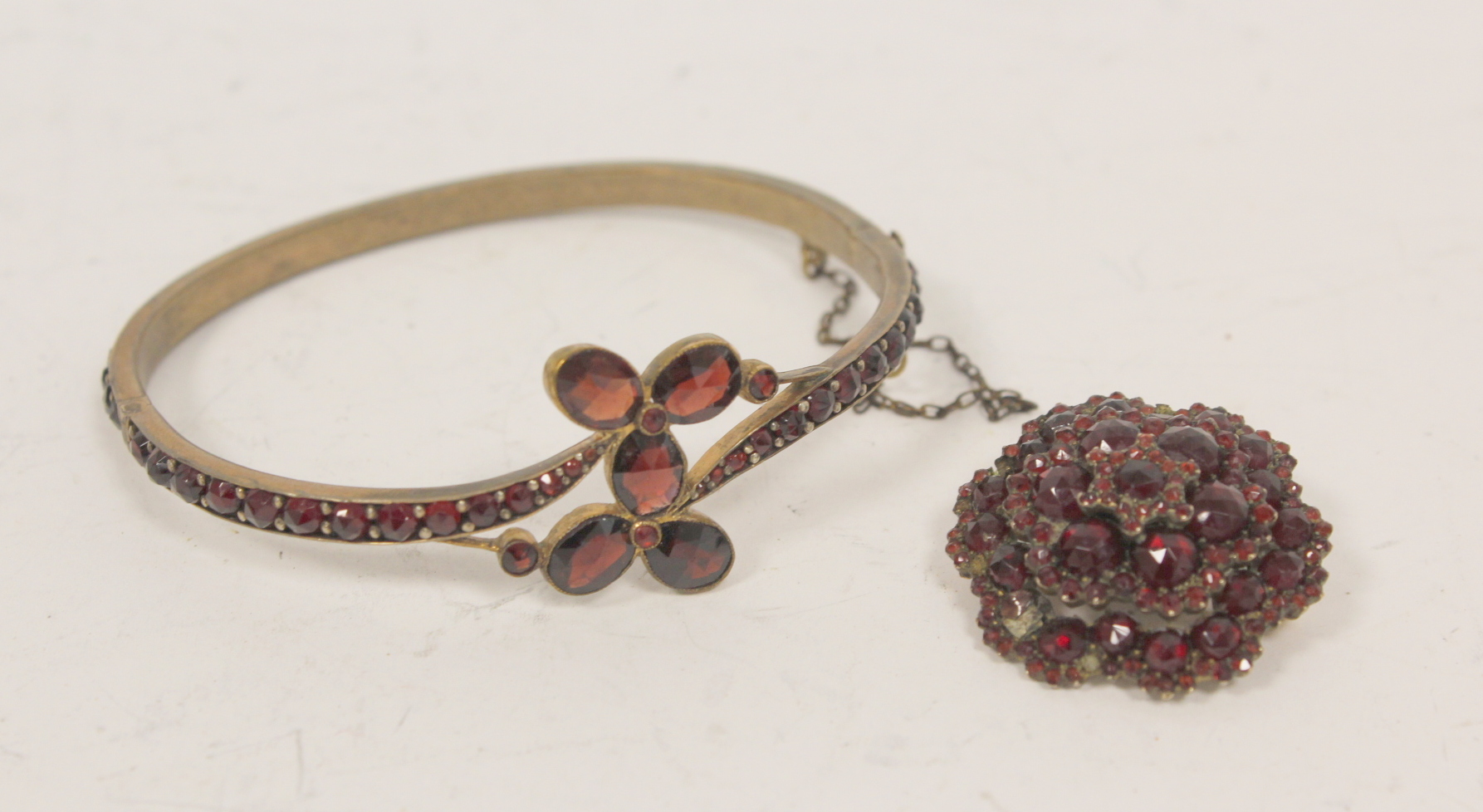 Victorian pyrope garnet hinged bangle in 'garnet' gold and a similar cluster brooch. (2).