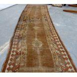 Turkish wool runner with geometric medallions and borders in muted palette, 285cm x 83cm, well worn.