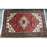 Modern Persian rug with central flowerhead medallion on red field, 150cm x 100cm.
