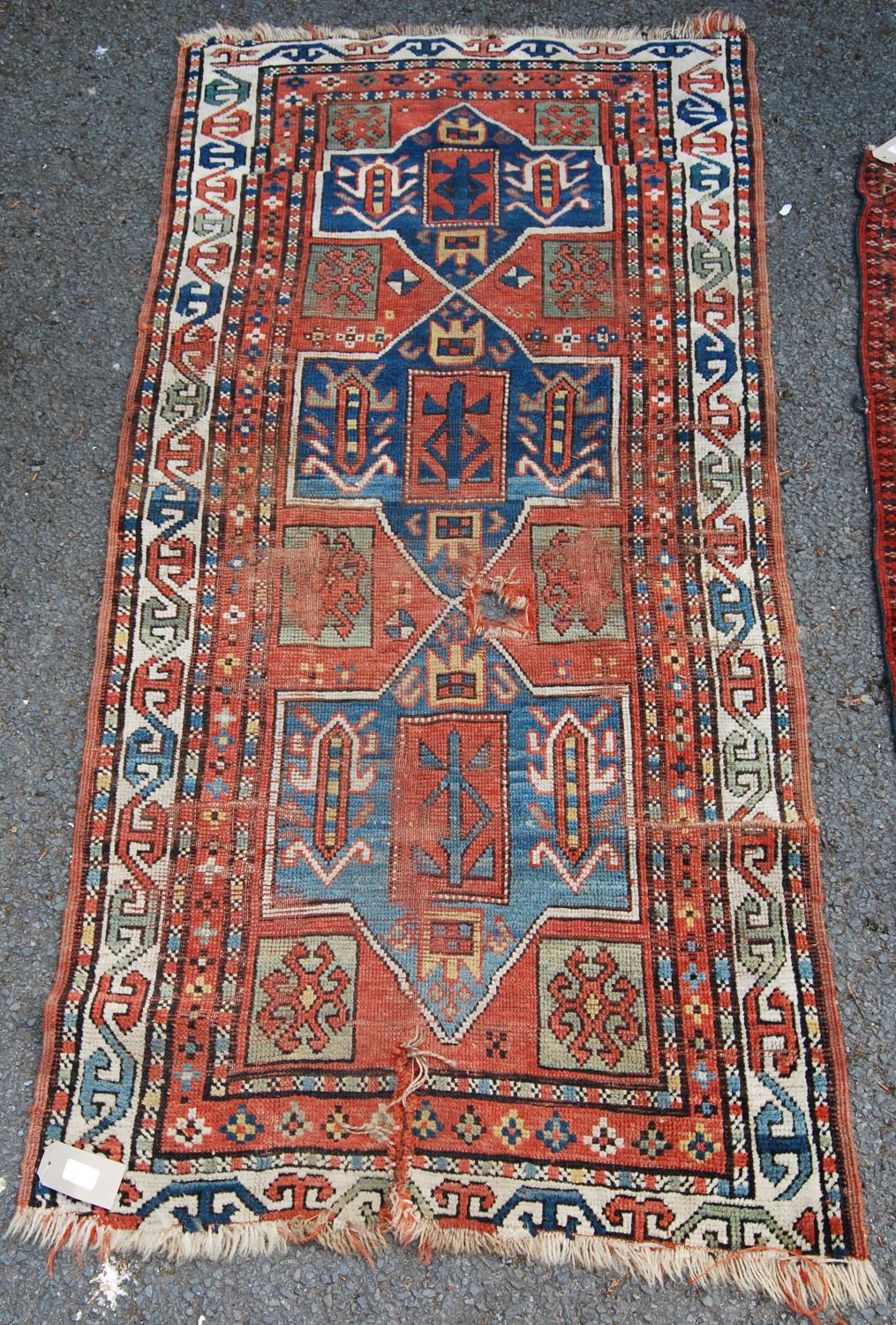 Persian rug, the three shaped blue panels over red ground, green squares and border, 190cm x 91cm.