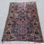 Persian rug with central medallion, faded red ground, geometric spandrels and floral border, 138cm x