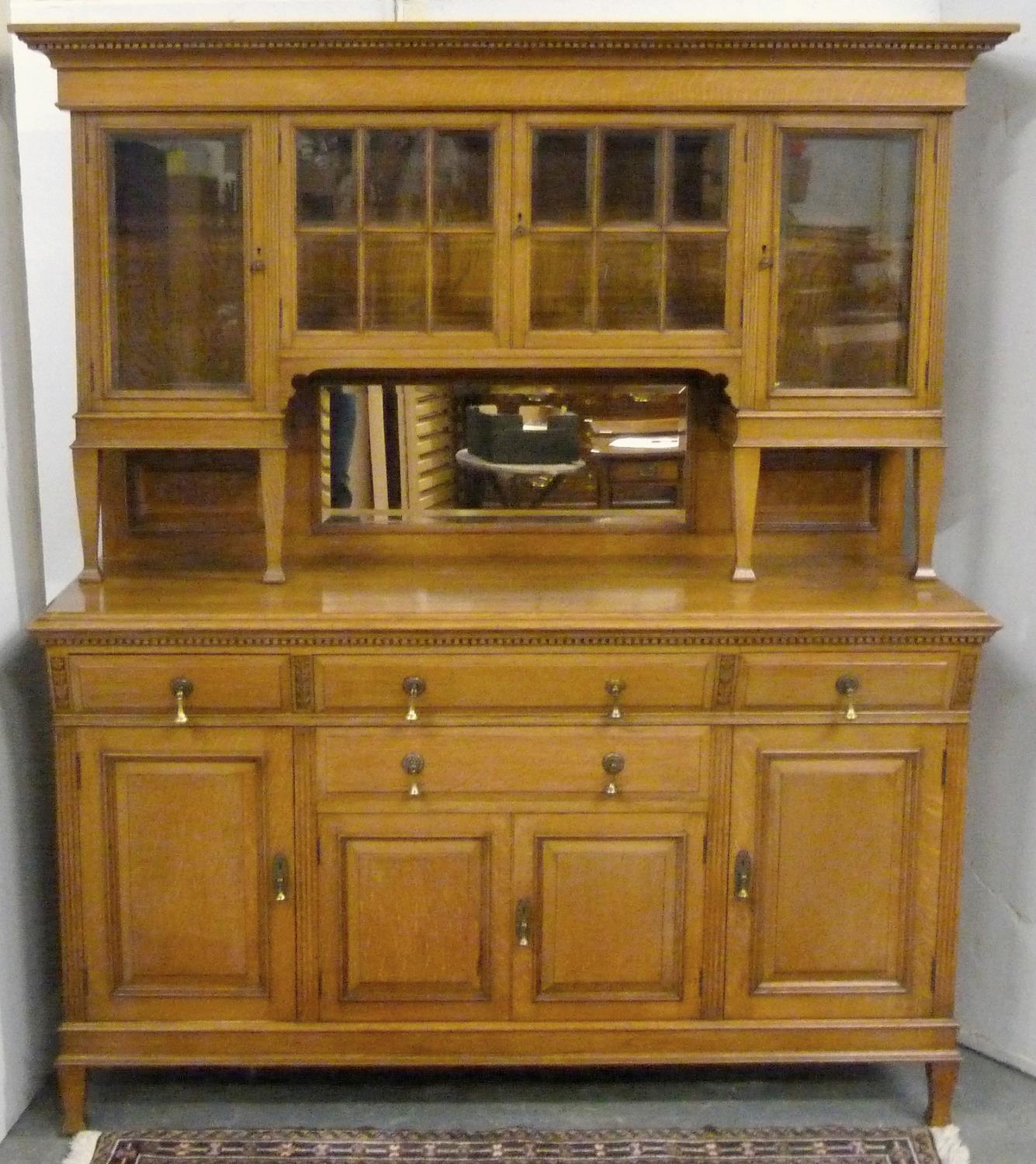 Oak Art Nouveau style dining room suite comprising a dresser, the upper section enclosed by glazed