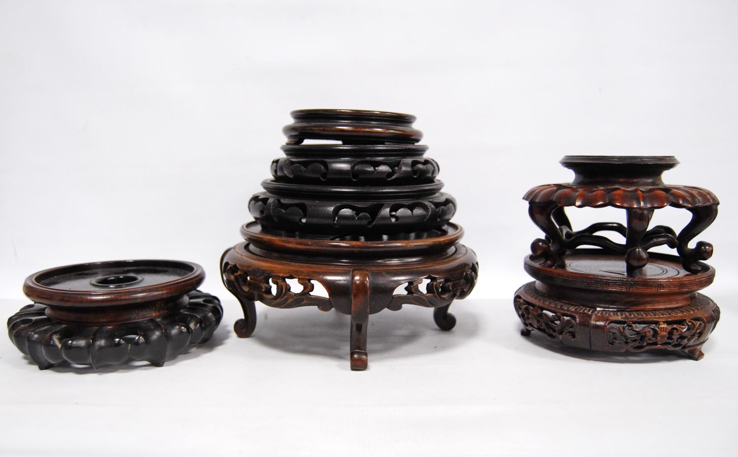 Eight oriental carved wooden stands.