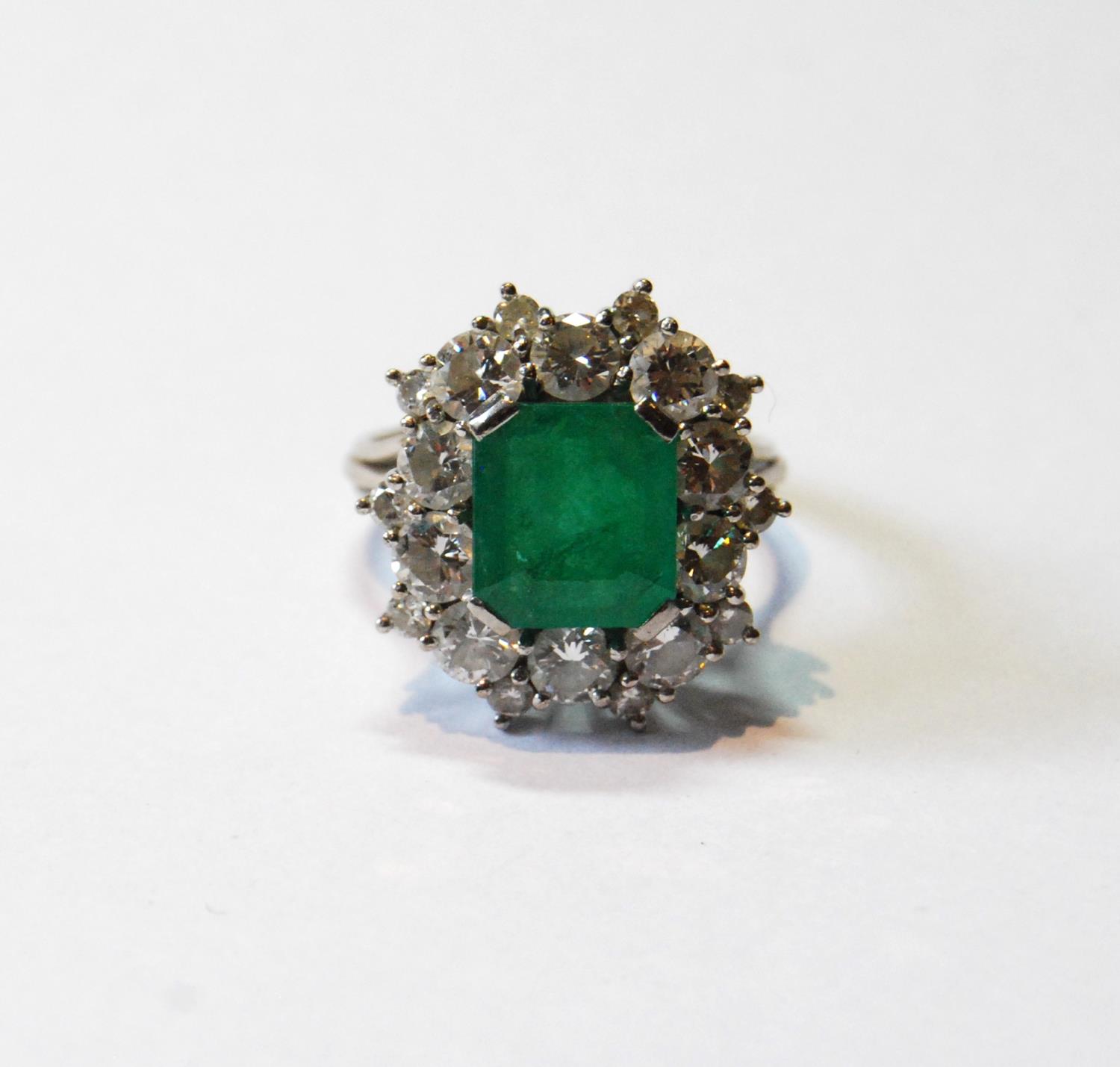 Diamond and emerald oval cluster ring with rectangular emerald and twenty diamond brilliants in