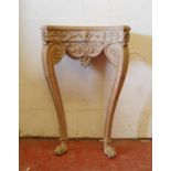 Limed wood console table, the concave beaded top over mask carved frieze, acanthus mounted