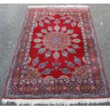 Isfahan rug, the central floral rosette over red ground, spandrels and triple floral border, 190cm x