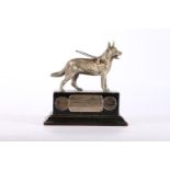 White metal model of an Alsatian mounted on wooden plinth base with plaques inscribed "Presented