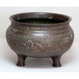 Oriental bronze censer of circular form on three plain drawn feet with dragon motifs on scroll