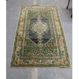 Persian rug in green, orange, cream & blue wool, the central hexagonal field with stylised floral