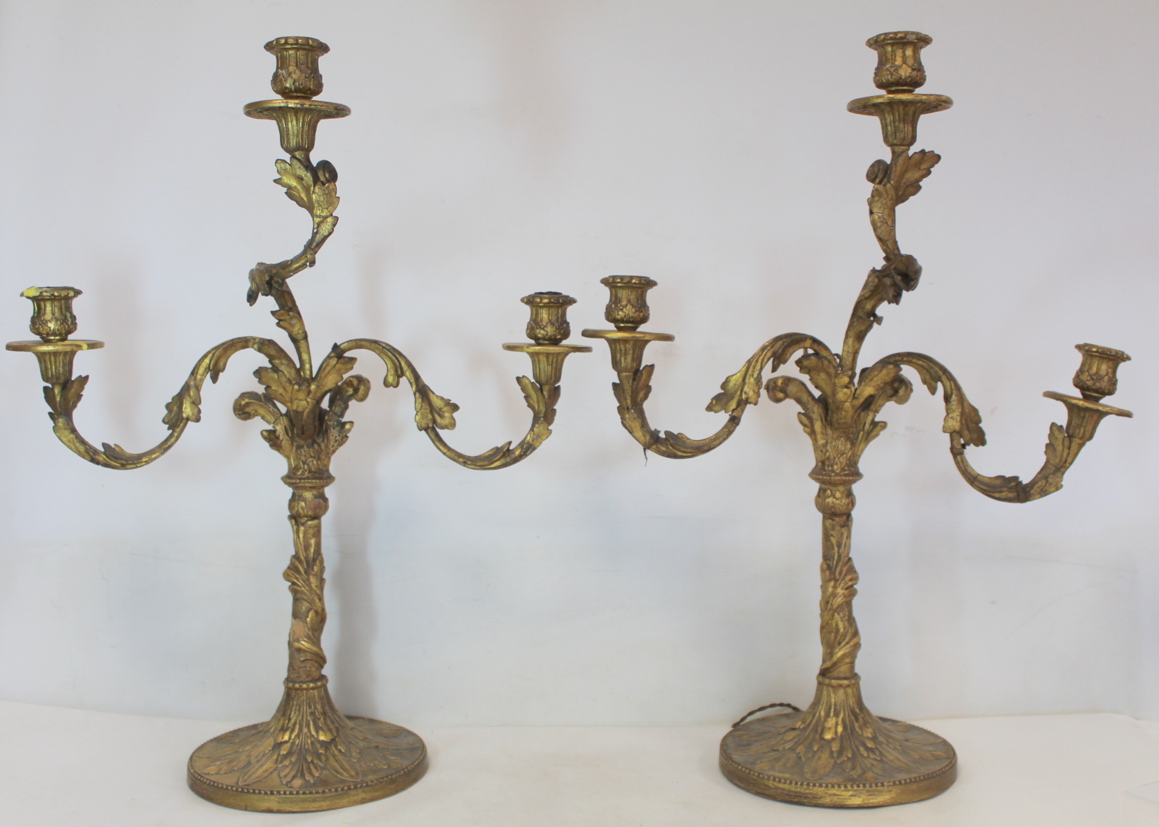 Pair of giltwood candelabra, each with three sconces on circular drip trays and scrolling foliate