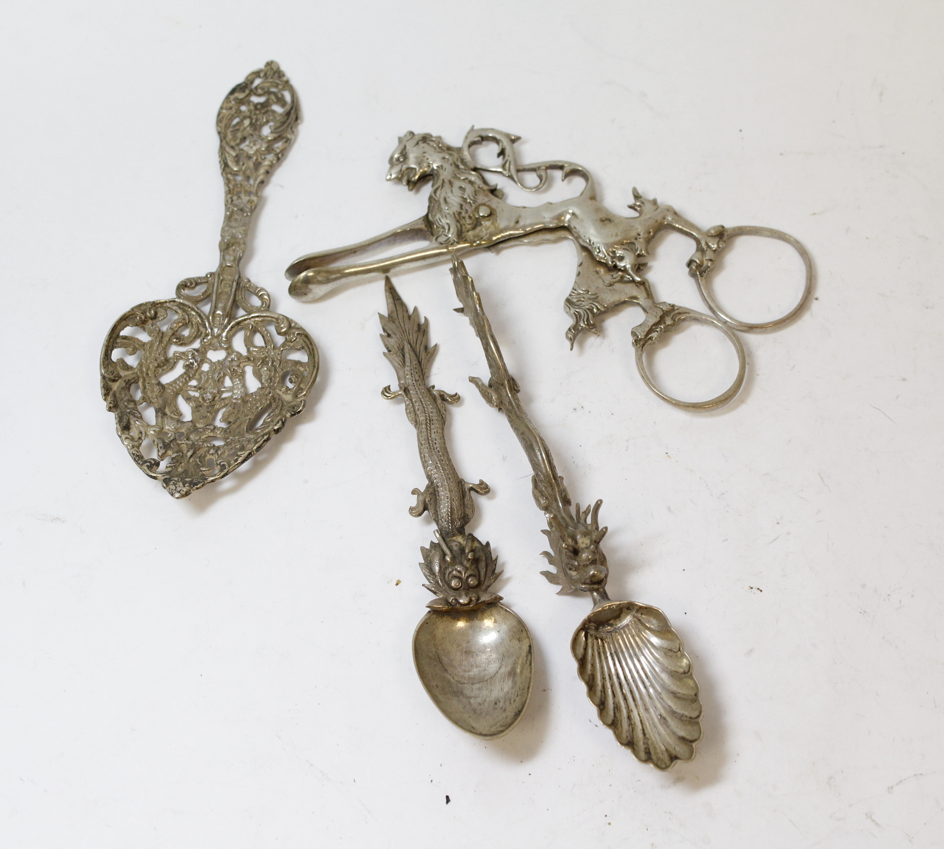 Silver ribbon puller modelled as a lion, 'fantasy' marks; two Chinese spoons and another, (London)