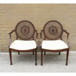 A pair of Sheraton revival mahogany open elbow chairs, the bergere caned circular backs with central