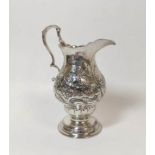 Silver cream jug of baluster shape, crested, with embossed flowers and scrolls upon circular moulded