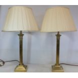Pair of brass table lamps of corinthian column form on stepped square plinth base with pleated cream