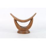An African carved wooden neck rest, the U shaped double supports carved with twisted rope