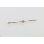 Unhallmarked yellow metal bar brooch set with three diamonds, the central stone approximately 0.