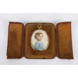 Portrait miniature depicting a young boy, held within an oval gilt metal frame within a leather