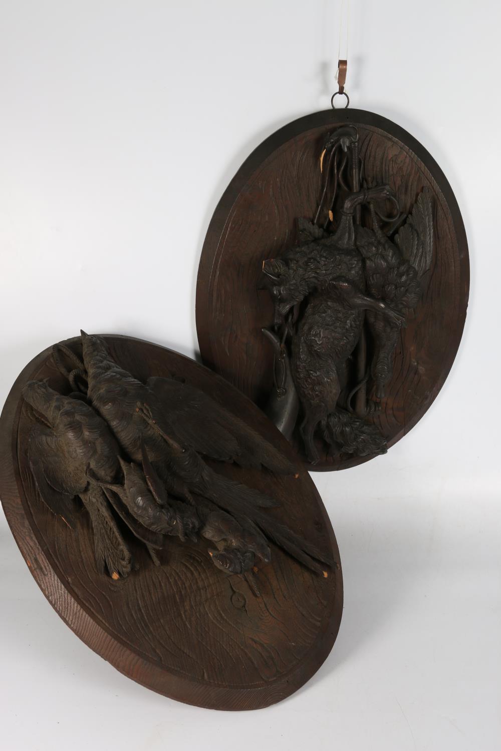 A pair of Black Forest style carved wood hunting trophy plaques with game birds on oval mount,