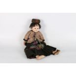 A Chinese late 19th or early 20th century doll with wooden body, straw stuffed legs and painted