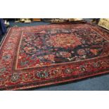 Large Persian carpet, the central dark blue ground with flowers and central eight leaved floral