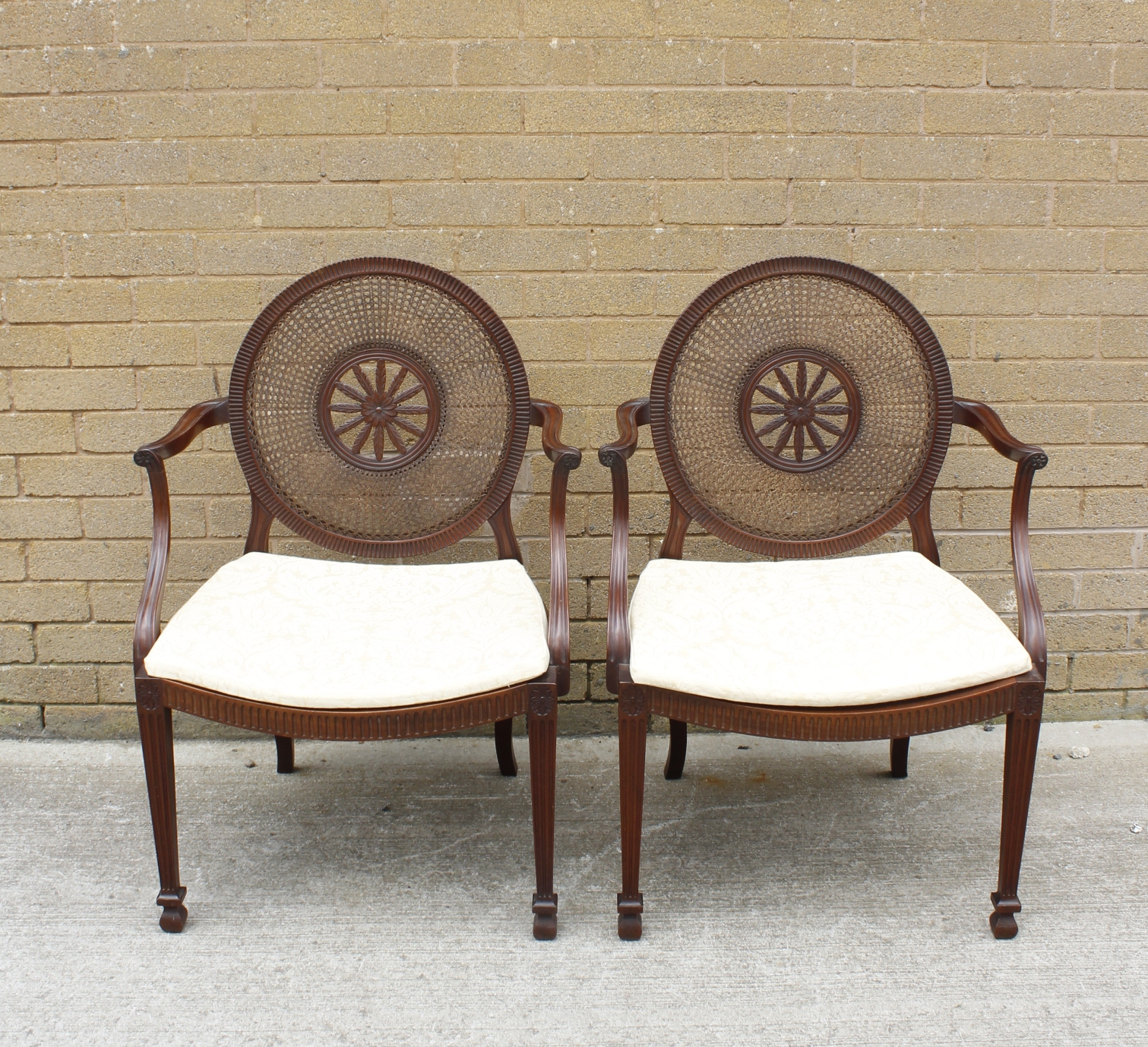 A pair of Sheraton revival mahogany open elbow chairs, the bergere caned circular backs with central