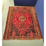 Hamadan rug decorated with three geometric medallions, surrounded by floral motifs on a red