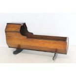 19th century mahogany doll's cradle with shaped hood on two solid rockers, 50cm long.