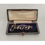 Edwardian gold brooch with scrolls of three sapphires and diamonds in gold and silver.