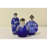 Three Chinese blue overlay glass snuff bottles, one bearing a relief of a leaping carp with