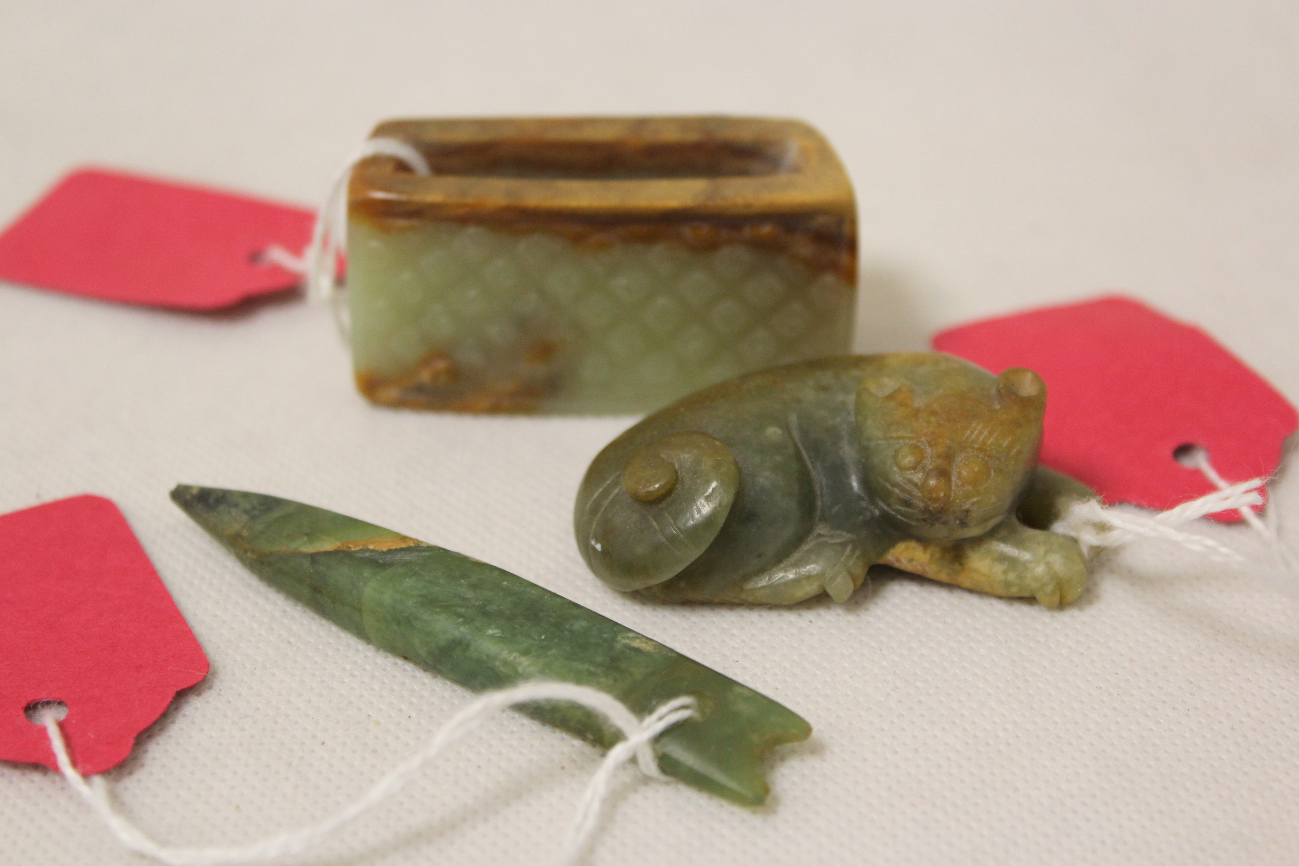 Three Chinese archaic and archaised jade figures to include a repose cat figure, a rectangular