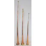 Three copper coach horns, with brass and white metal mounts, 122cm, 101cm and 98cm.  (3).