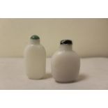 Two Chinese white glass snuff bottles to include one with a dark green glass stopper, the other of