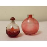 Two Chinese red glass snuff bottles, one of spherical form with incised lotus leaf to base, the