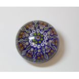 Millefiori glass paperweight of circular globular form with polychrome canes on blue ground,