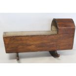 19th century stained pine doll's cradle with shaped hood on two solid rockers, 43cm long.