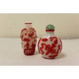 Two Chinese glass snuff bottles to include a red glass overlay bottle of spherical form decorated