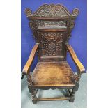 Wainscot carved oak armchair, circa 19th century, with a scroll shaped top above a carved back rest,