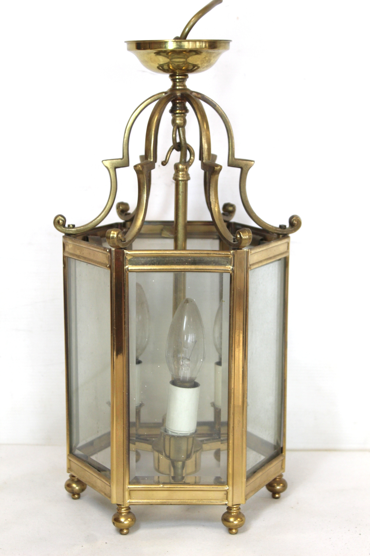 Georgian style brass hall lantern of hexagonal form with bevelled glass panels, domed scroll