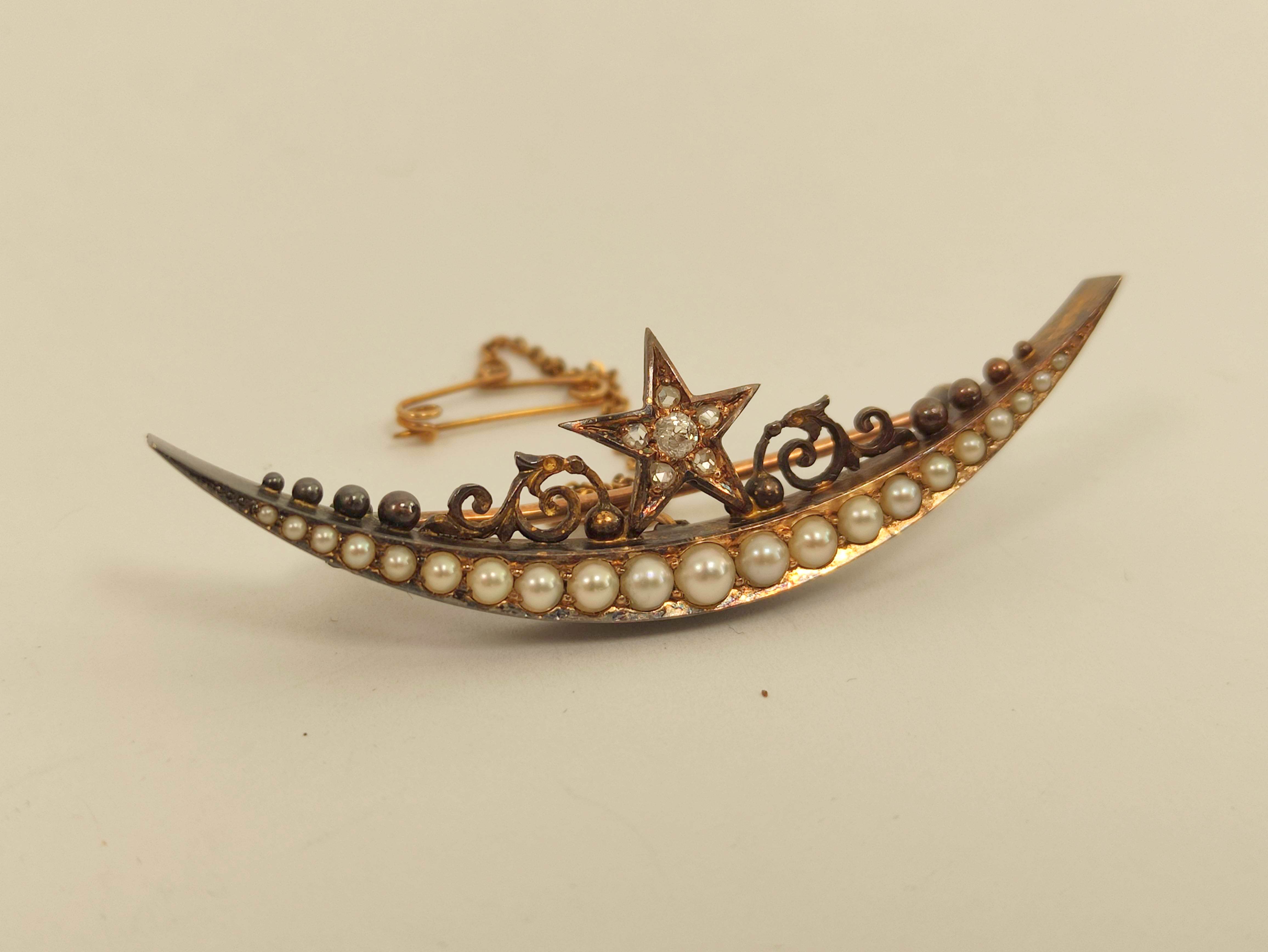 Victorian gold crescent brooch with graduated pearls and diamond set star. 5.4g.